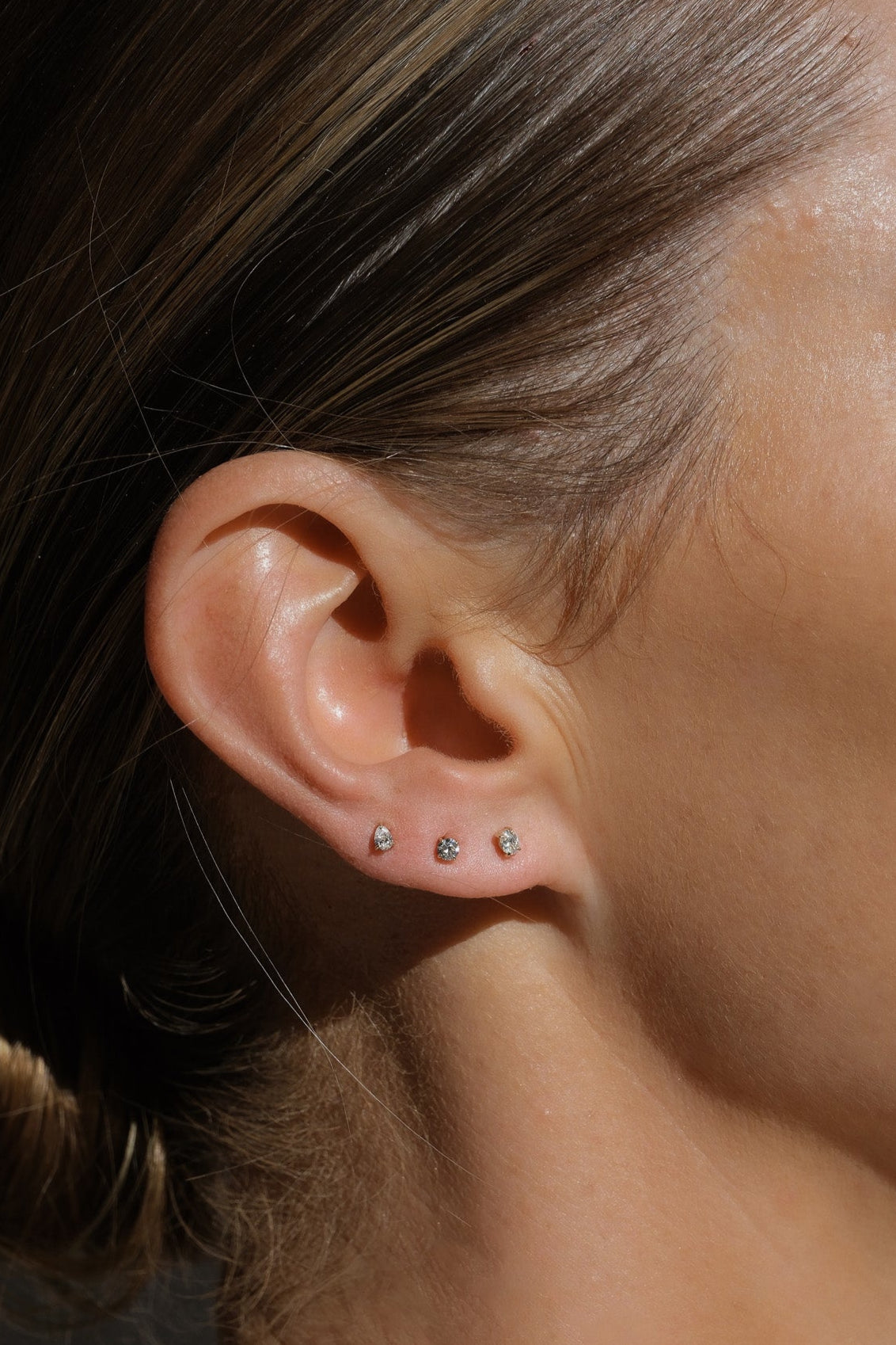 Close-up of an ear with earrings and hair pulled back