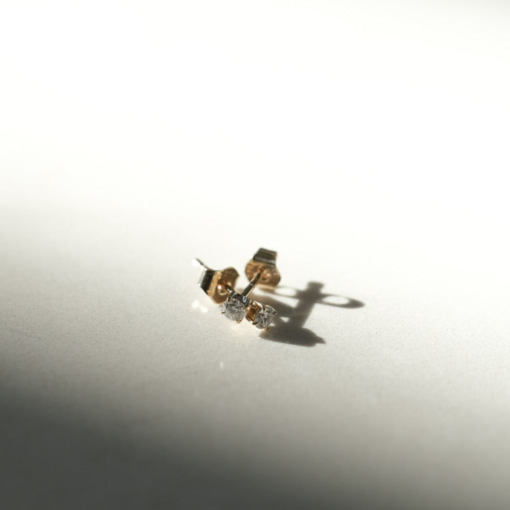 Gold earrings on a white surface with a soft shadow
